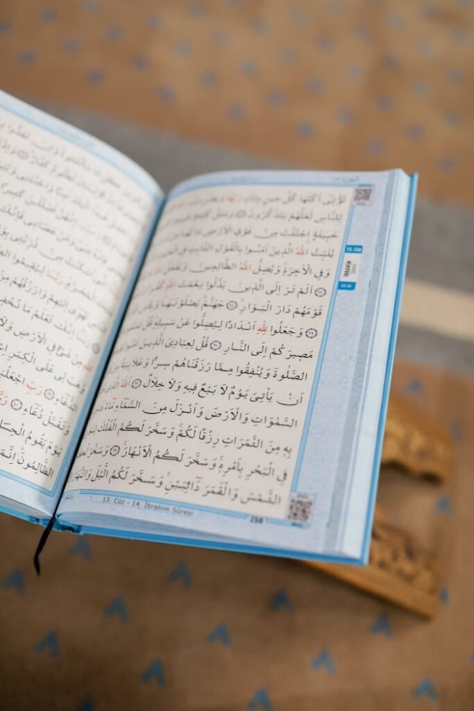 Open Quran on a wooden stand, showcasing Arabic text with a patterned background.